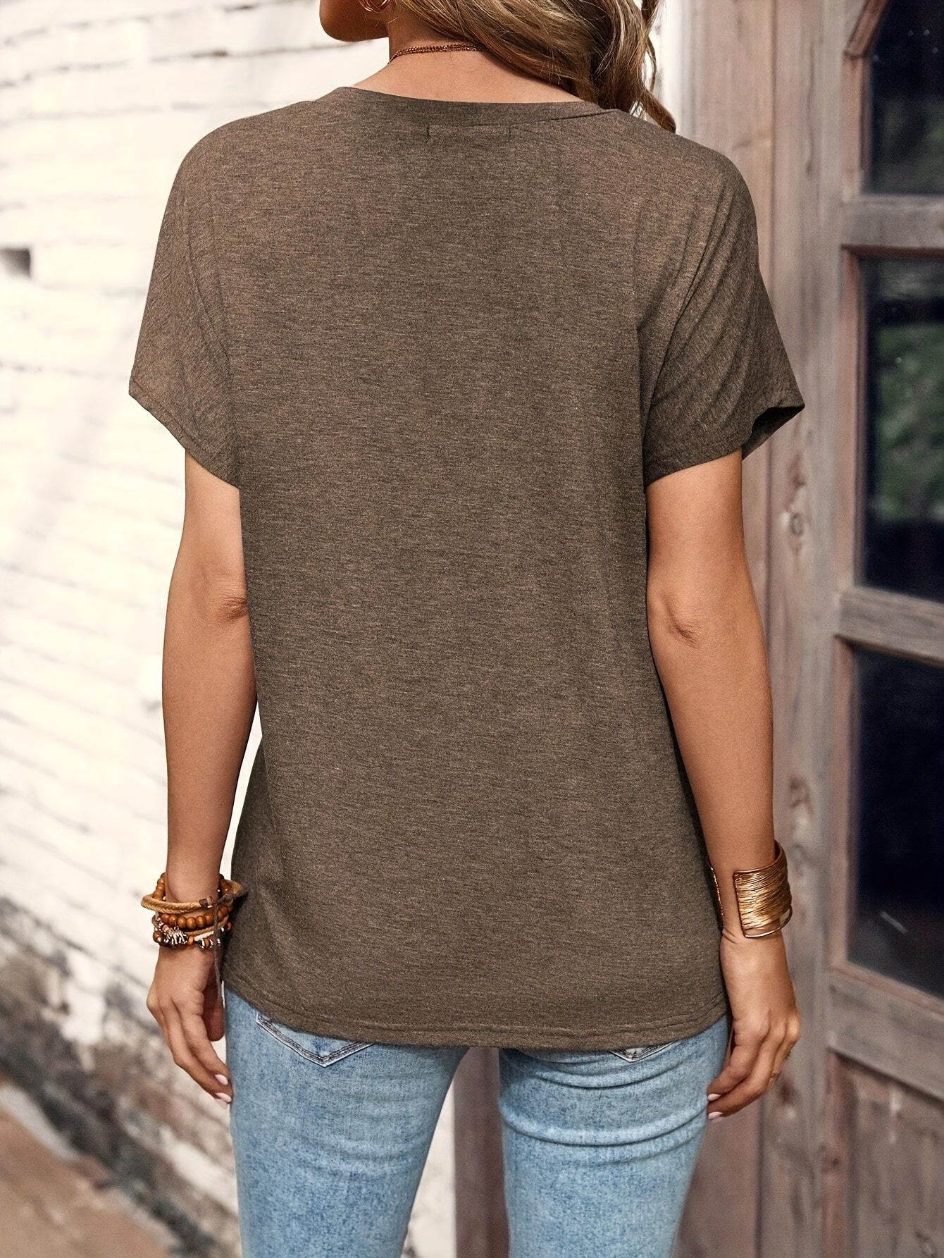 Back view of a woman wearing an elegant chic summer top in brown paired with light blue jeans